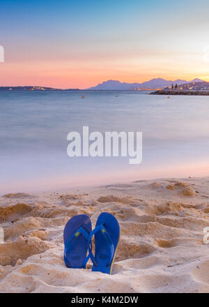 Flip Flops auf einem sandigen Strand bei Sonnenuntergang Stockfoto