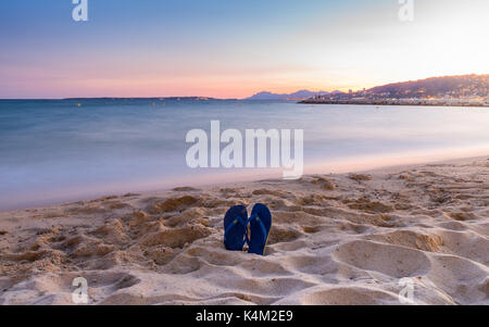 Flip Flops auf einem sandigen Strand bei Sonnenuntergang Stockfoto