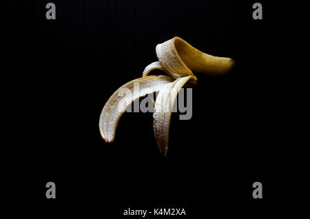Banane schälen isoliert auf Schwarz Stockfoto