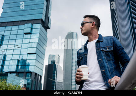 Junge Mann trägt blaue Jeansjacke beim Tagträumen im Freien i Stockfoto