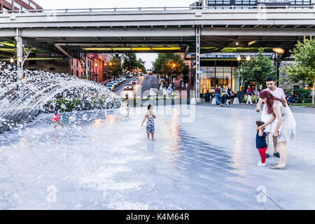 Washington DC, USA - August 4, 2017: Junge Kinder spielen im Wasser Brunnen in Georgetown Park in den Abend mit Wasser spritzen Stockfoto