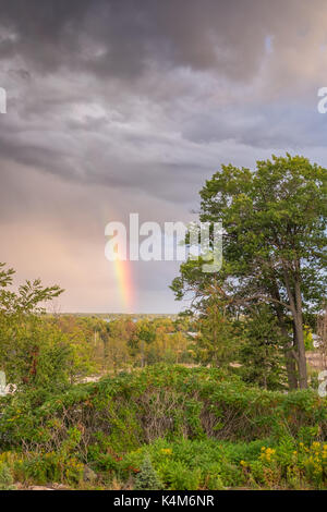 Ein bunter Regenbogen erscheint in der Ominösen Himmel nach schweren Gewittern. Stockfoto