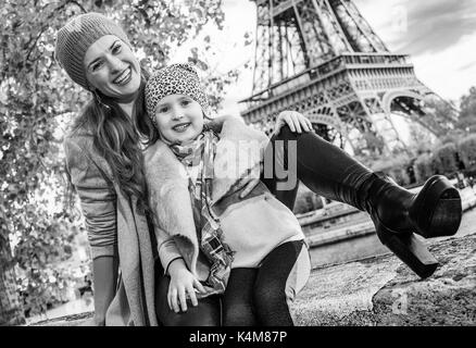 Herbst Kurzurlaube in Paris mit der Familie. glückliche Mutter und Tochter Reisende am Ufer in der Nähe von Eiffel Turm in Paris, Frankreich auf der Brüstung sitzen Stockfoto