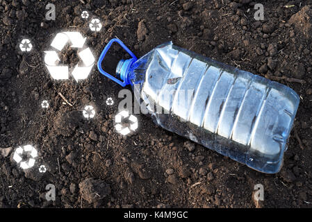 Geleert PET 5 Kunststoff Gallone Trinkwasser Behälter in braun Erde mit Recycling Zeichen auf dem Boden verstreut Stockfoto