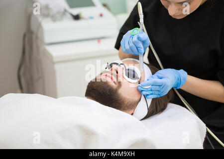 Kosmetikerin während der Männer oxybrasion Therapie Stockfoto