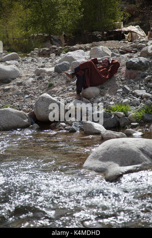 Berber Mann entspannt durch Fluß während der Souk von setti Fatma, Ourika Valley, Atlas, Marokko Stockfoto