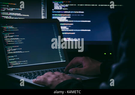 Hacker arbeiten an einen Code in dunklen Zimmer. Programmierung Code auf dem Bildschirm. Internet Kriminalität Konzept Stockfoto