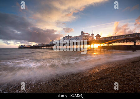 Brighton Pier bei Sonnenuntergang mit dramatischen Himmel und Wellen spülen den Strand, Brighton, East Sussex, England, Vereinigtes Königreich, Europa Stockfoto