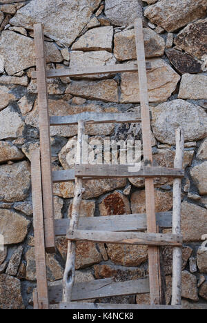 Rustikale Holzleitern gegen eine Mauer aus Stein Stockfoto