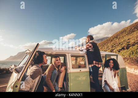 Freunde auf Roadtrip entspannend durch die Van. Gruppe von Mann und Frauen zusammen in einem alten minivan reisen. Stockfoto