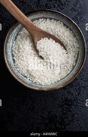 White Sushi Reis in der Schüssel auf dem Schwarzen Tisch. Draufsicht auf Reis. Stockfoto