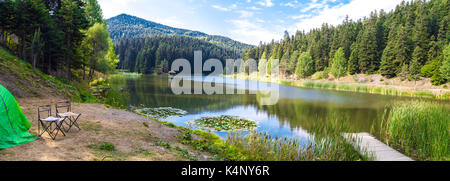 Outdoor Camping in Abenteuer. Ausblick auf den kleinen See Akgol in Sinop Ayancik, um große Berge mit hohen Pinien an bewölkten Himmel Hintergrund. Stockfoto