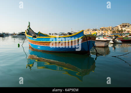 MARSAXLOKK, MALTA - 23. AUGUST 2017: Traditionelle bunte Luzzu Fischerboote ankommen und Verankerung in den frühen Morgen im Hafen von Marsaxlokk Stockfoto