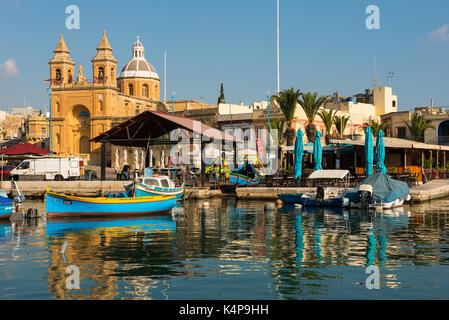 MARSAXLOKK, MALTA - 23. AUGUST 2017: Traditionelle bunte Luzzu Fischerboote ankommen und Verankerung in den frühen Morgen im Hafen von Marsaxlokk Stockfoto