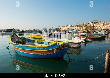 MARSAXLOKK, MALTA - 23. AUGUST 2017: Traditionelle bunte Luzzu Fischerboote ankommen und Verankerung in den frühen Morgen im Hafen von Marsaxlokk Stockfoto