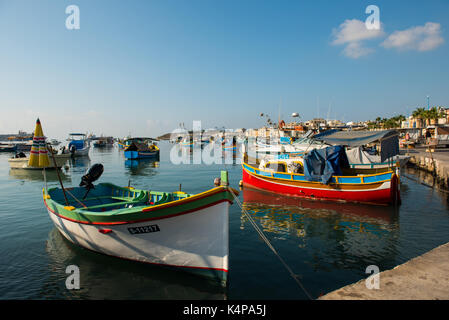 MARSAXLOKK, MALTA - 23. AUGUST 2017: Traditionelle bunte Luzzu Fischerboote ankommen und Verankerung in den frühen Morgen im Hafen von Marsaxlokk Stockfoto