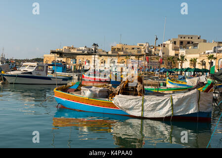 MARSAXLOKK, MALTA - 23. AUGUST 2017: Traditionelle bunte Luzzu Fischerboote ankommen und Verankerung in den frühen Morgen im Hafen von Marsaxlokk Stockfoto