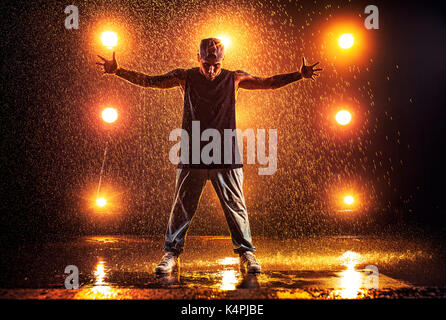 Junger Mann Breakdancer im Club mit Licht und Wasser. Tattoo am Körper. Stockfoto