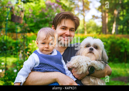 Vater mit Sohn und Hund zusammen Porträt im Sommer grün Garten Stockfoto