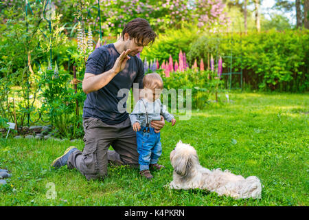 Vater lehre Sohn, wie der Hund im Sommer zu Befehl Green Garden Stockfoto