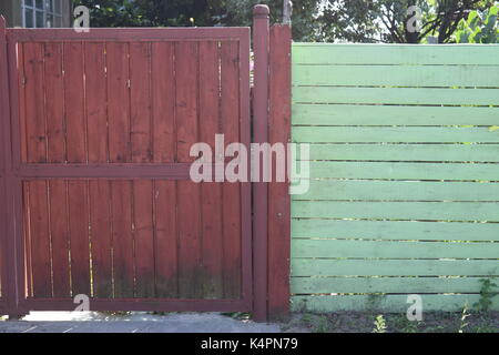 Braun lackierten Holz- Zaun neben einer Wand Stockfoto
