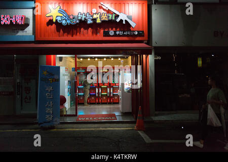 Ein Mann spielt allein in der Spielhalle Schießstand nach Einbruch der Dunkelheit in Sinsa - Hund, Gangnum-gu, Seoul, Südkorea. Stockfoto