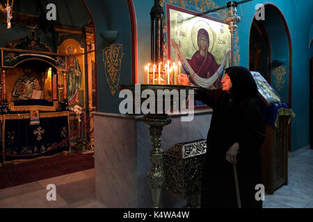 Ein christlich-orthodoxer Gläubiger zündet Kerzen in der Kirche des griechisch-orthodoxen Klosters an, bekannt als Gethsemane Metoxion, wo eine berühmte Ikone der heiligen Maria das ganze Jahr über stattfindet (außer in der Nacht vom 25. August, in der sie entlang einer Prozession bewegt wird, An das Grab der Maria auf der Slop des Ölbergs für die Woche der Feier der Himmelfahrt der Maria in den Himmel) befindet sich auf der Seite der Kirche des Heiligen Grabes im christlichen Viertel Altstadt Ost-Jerusalem Israel Stockfoto