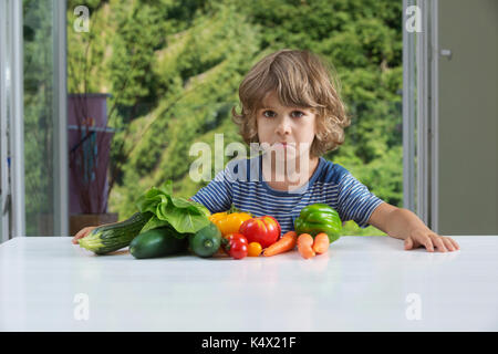 Cute little boy am Tisch sitzen, unglücklich mit seinem Gemüse essen, schlechte Essgewohnheiten, Ernährung und gesunde Ernährung Konzept Stockfoto