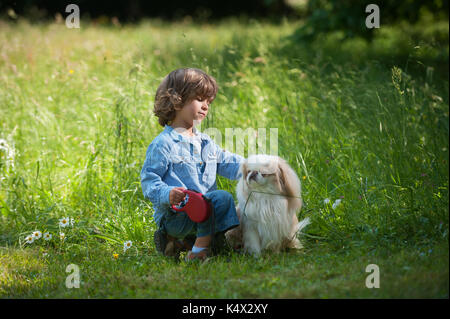 Süße kleine Junge, der seinen Hund kuscheln in der Natur Stockfoto