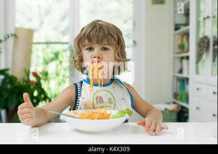 Porträt von einem niedlichen kleinen Jungen, ein Durcheinander beim essen Pasta zum Mittagessen Stockfoto