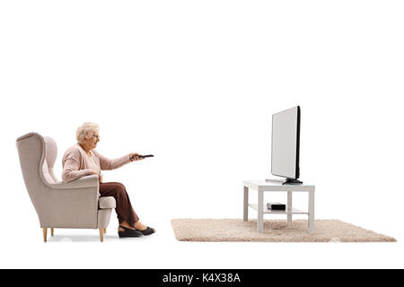 Ältere Frau im Sessel vor dem Fernseher sitzt und Wechseln der Kanäle auf weißem Hintergrund Stockfoto