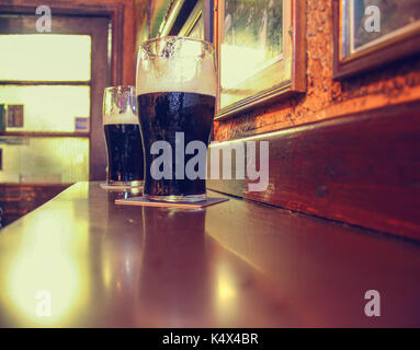 Zwei Gläser der berühmten schwarzen Irish Stout im Irish Pub auf Holzstab Stockfoto