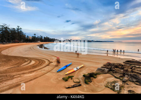 Früher Morgen Manly Strand bei Ebbe mit aktiven Menschen gehen zum Schwimmen und Laufen Kajaks über glatte Wasser des Pazifischen Ozeans aus australischen Küste in Sy Stockfoto