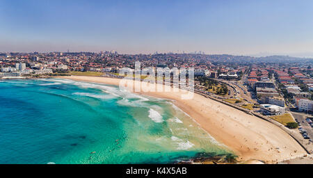 Unberührte klares Wasser von Sydney Bondi Strand mit hellem Sand und CBD Türme am Horizont in Antenne kurz oberhalb des Strandes. Stockfoto