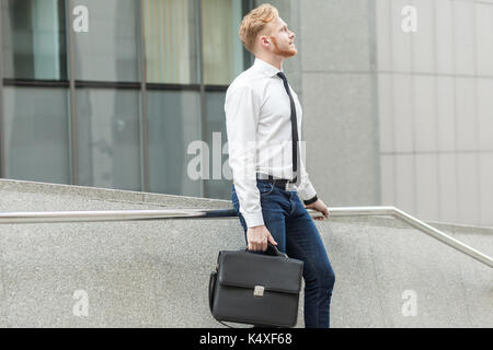 Junge Erwachsene gut gekleidete Geschäftsmann, Wundern und Träumen für einen neuen Job. Im Freien Stockfoto