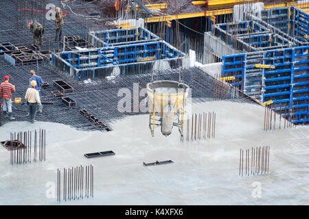 Bau der Grundstein des neuen Gebäudes. Luftbild der Baustelle Arbeitnehmer Nivellierung Zement in der Baustelle. Stockfoto