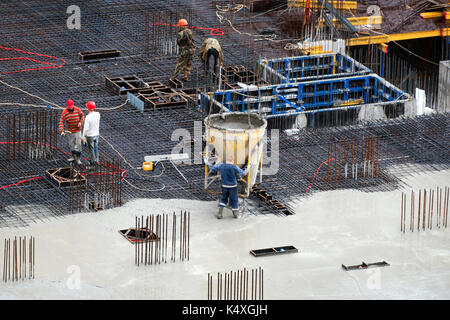 Bau der Grundstein des neuen Gebäudes. Antenne Blick von oben auf die Baustelle Arbeitnehmer Nivellierung Zement in der Baustelle. Stockfoto