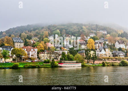 Heidelberg Stadt in Deutschland, am Fluss cıty mit charmanten Häusern auf einem nebeligen Hügel, umgeben von Herbstbäumen, Stockfoto