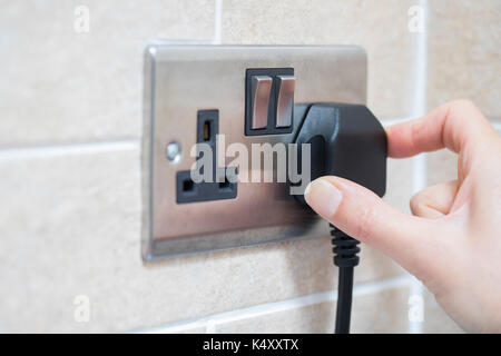 Hand, Stecker in die Steckdose Stockfoto