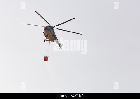 Feuerwehrmann Heli im Flug einen Wassereimer Stockfoto