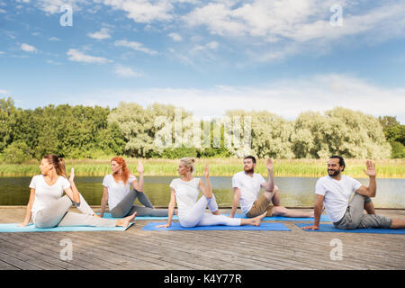 Menschen, die Yoga auf eine halbe Herrn der Fische darstellen Stockfoto