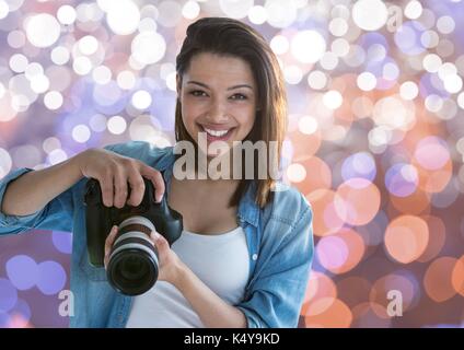 Digital composite Der junge Fotograf lächelnd mit der Kamera auf die Hände. Braun Weiß und Blau bokeh Hintergrund Stockfoto