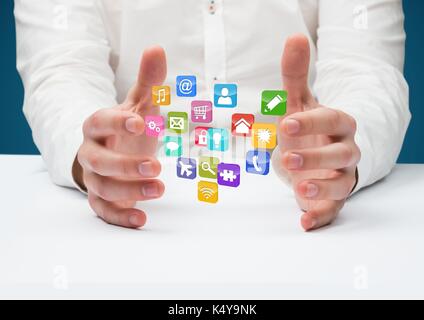 Digital composite der Hände mit Application Icons im Schreibtisch. Blauer Hintergrund Stockfoto