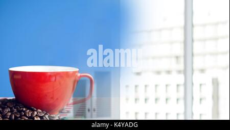 Digital composite der roten Kaffeetasse auf roten und weißen Tischdecke mit Bohnen gegen den blauen Hintergrund und blurry Büro tra Stockfoto