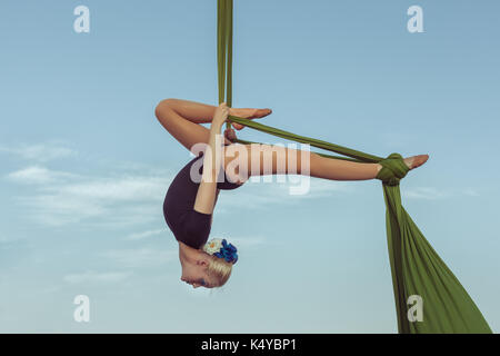 Frau Luft Gymnast führt einen Trick auf einer Hängematte hoch in den Himmel. Stockfoto