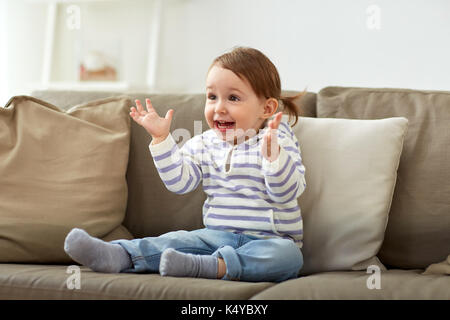 Glücklich lächelnde Baby Mädchen auf dem Sofa zu Hause sitzen Stockfoto