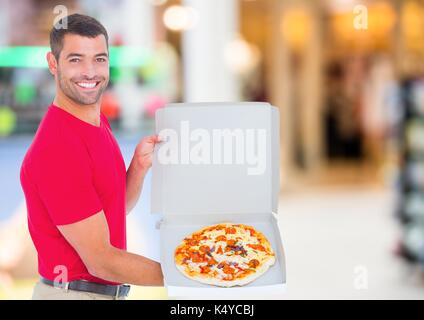Digital composite der Lieferung Mann mit Pizza gegen blurry Einkaufszentrum Stockfoto