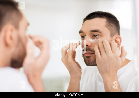 Junger Mann Anwendung Creme im Badezimmer zu Gesicht Stockfoto