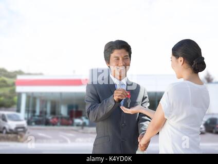 Digital composite der Geschäftsmann übergibt Autoschlüssel Frau an Auto Store Stockfoto