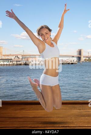 Digital composite der Frau in der Luft gegen Wasser und Skyline springen Stockfoto